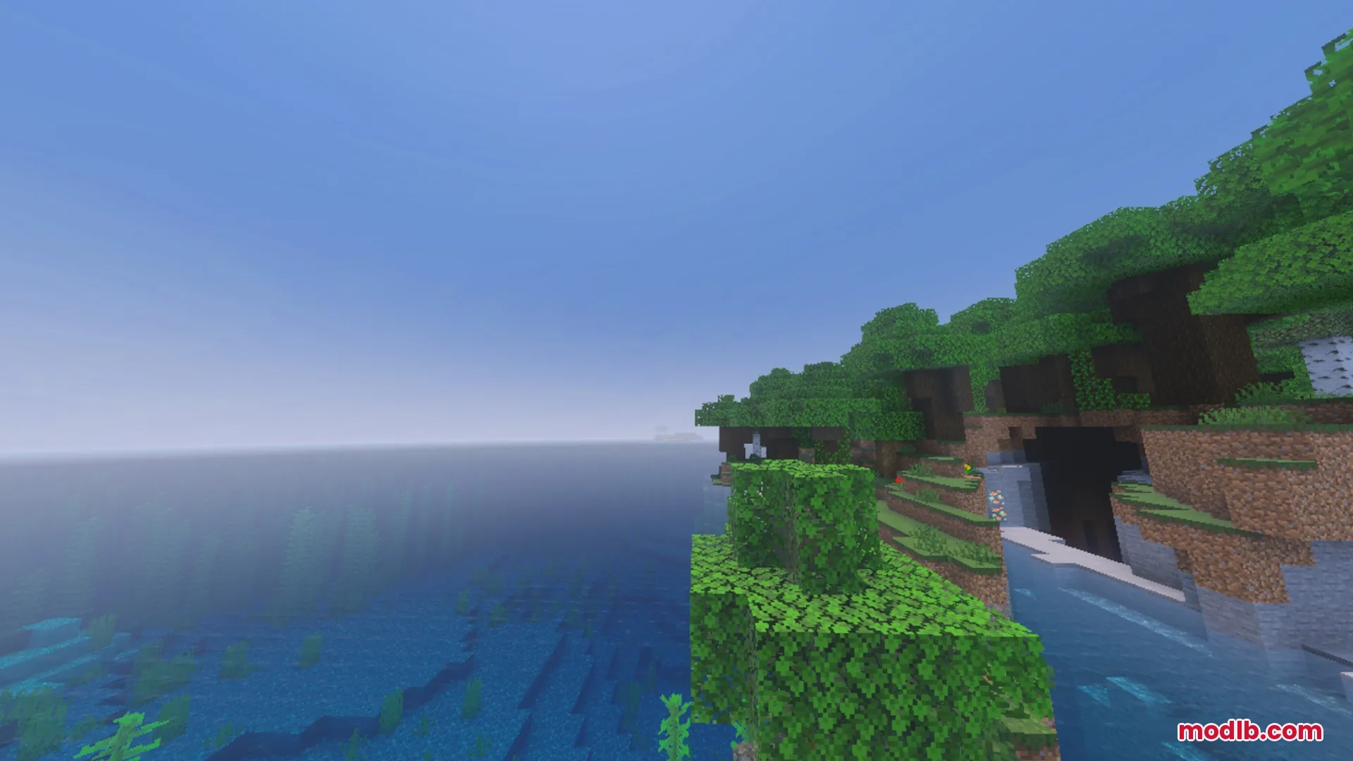 Better Waving Leaves Shader Screenshot 2 Lush green forest biome next to a vast blue ocean in Minecraft