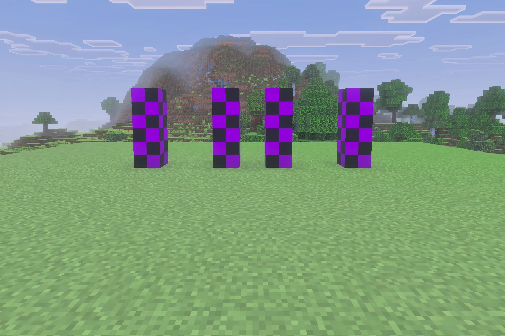 Four pillars of purple and black checkered blocks in a grassy landscape