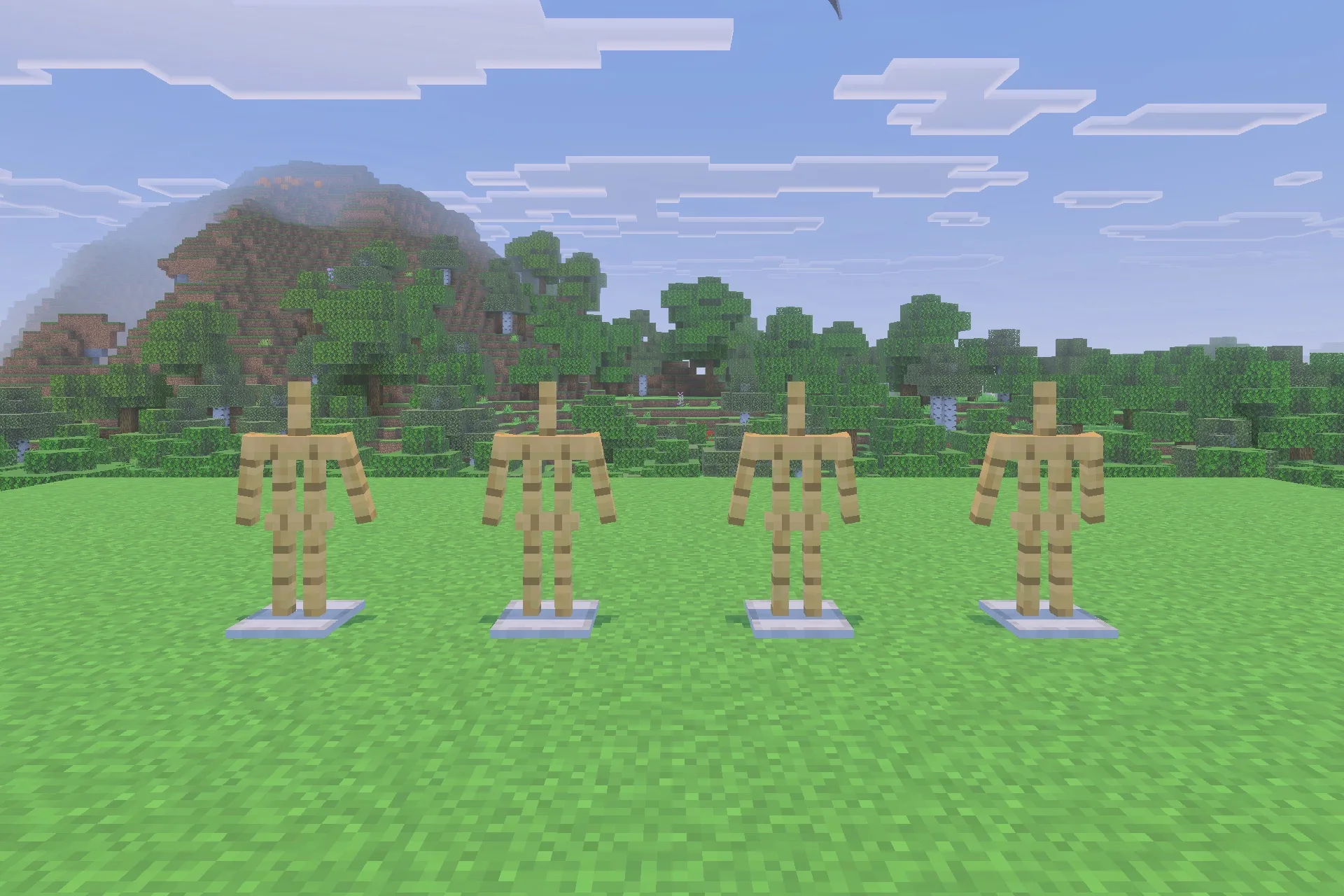 Four empty armor stands placed in a row on a grass field