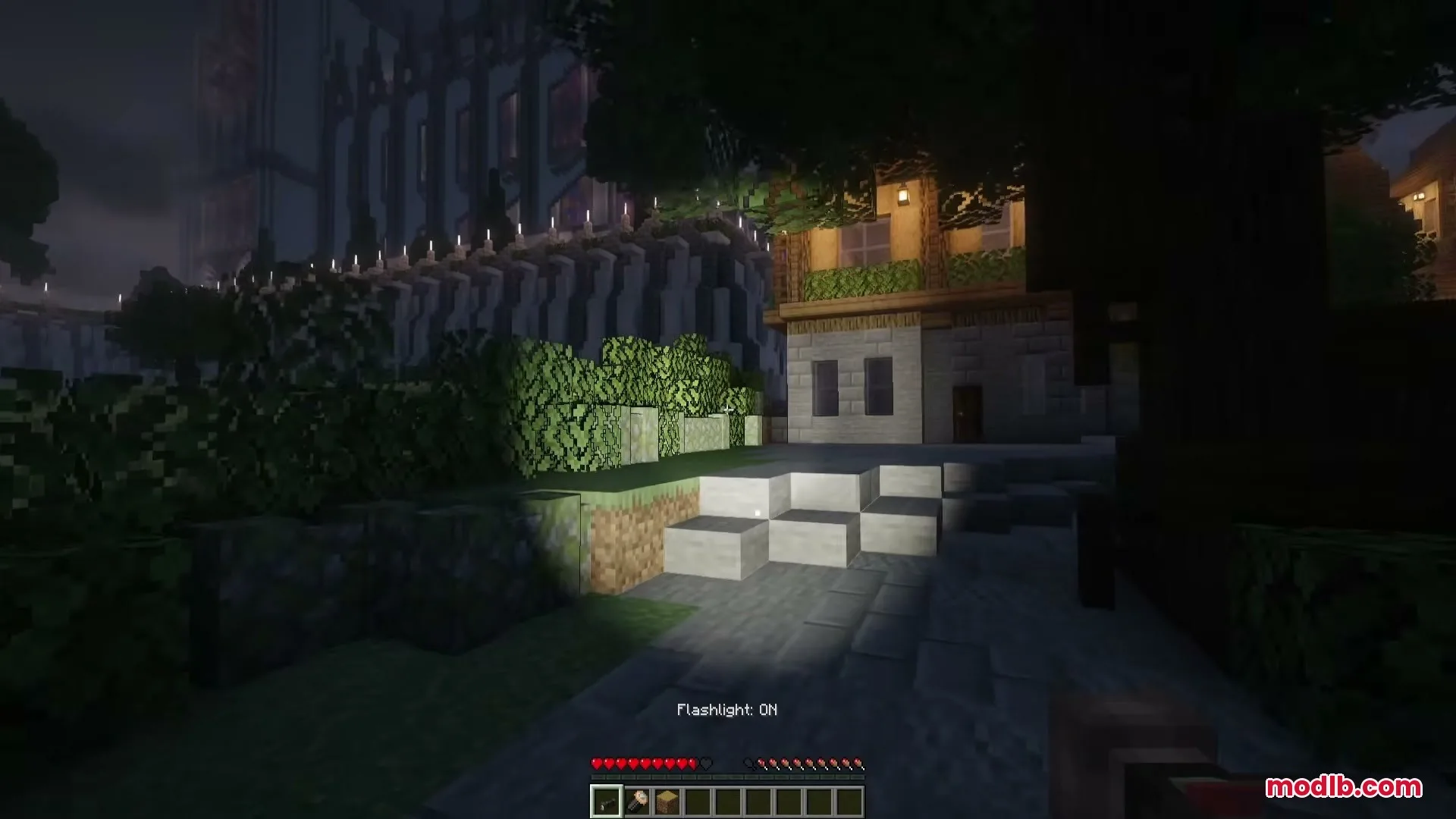 Flashier Flashlights Mod Screenshot 3 A player uses a handheld flashlight to light up a dark path with hedges