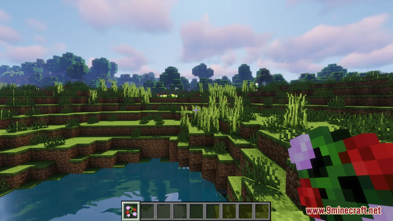 Player holding a colorful floral creeper item in a grassy landscape near water