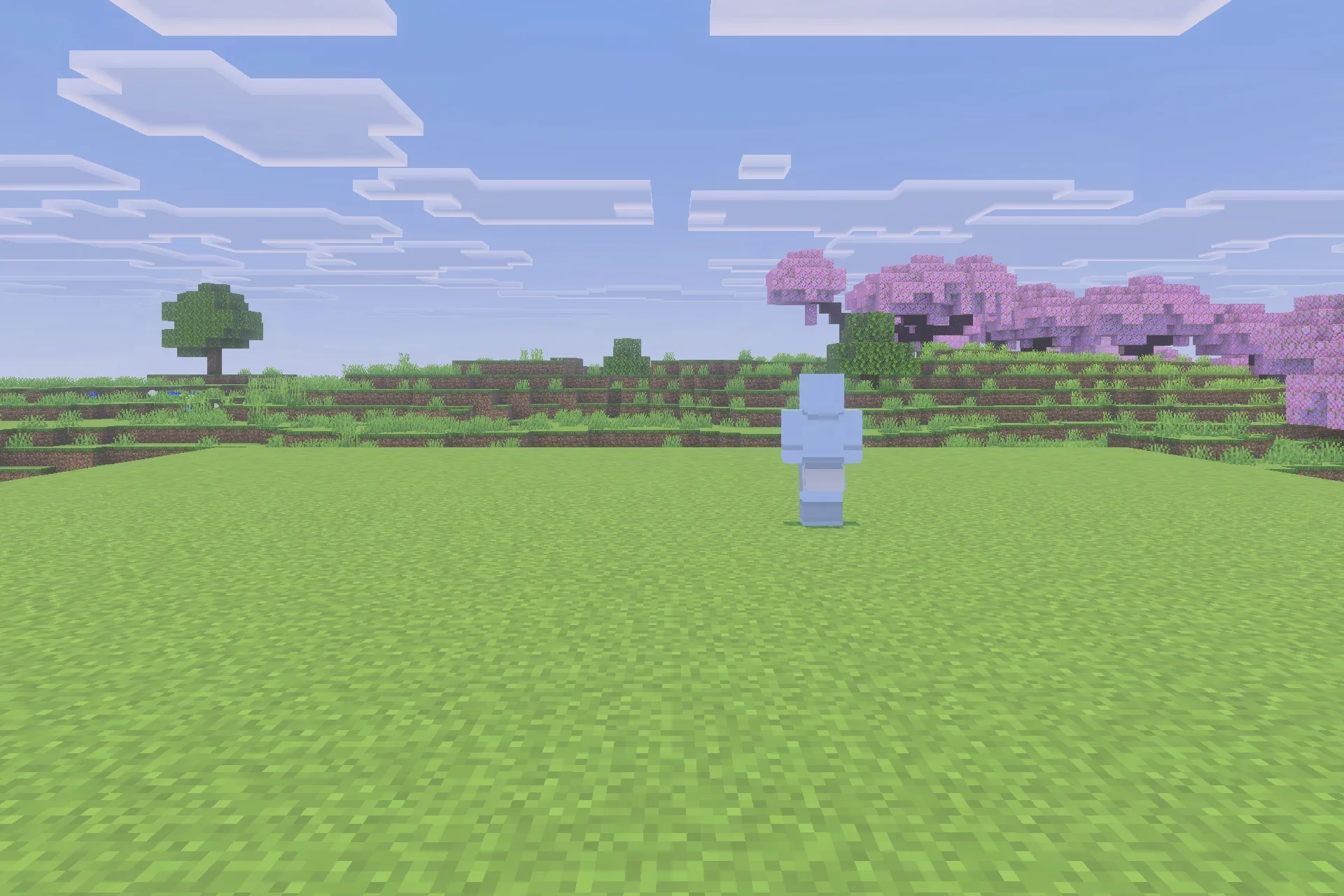 The transparent blue character model stands on a grassy field near pink trees