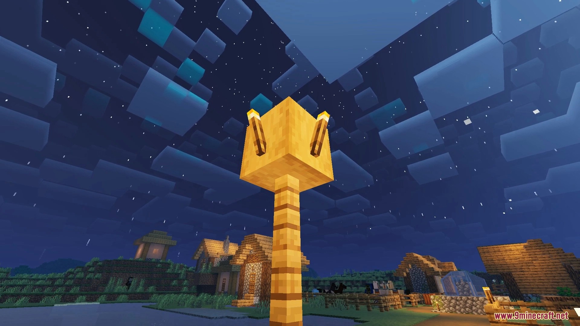 Nighttime view of a village with a glowing gold block lamp post