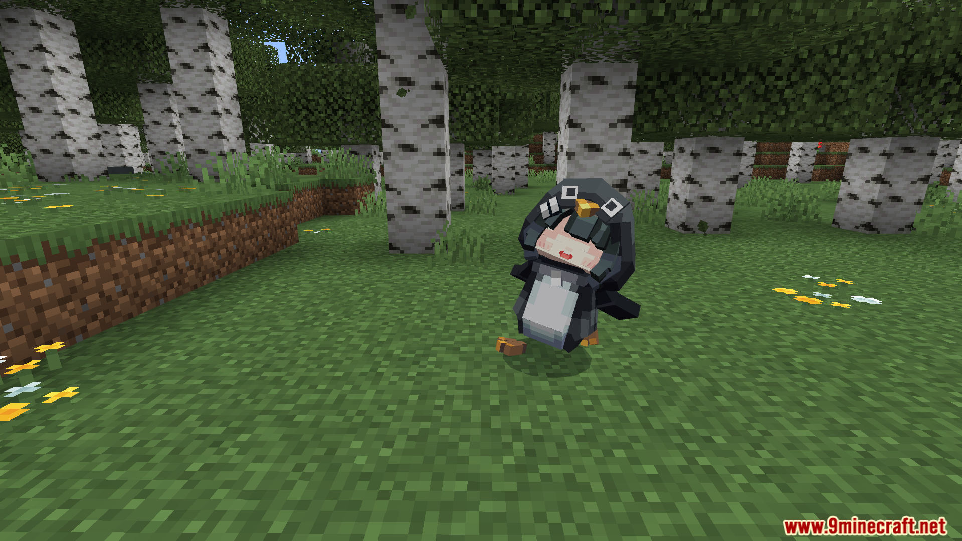 The small penguin mob with a human face sitting down on the grass