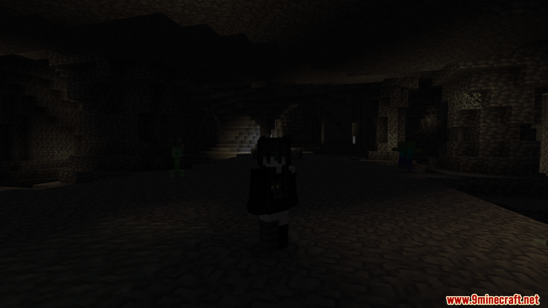 Player character standing in a dark cave near a creeper and a zombie