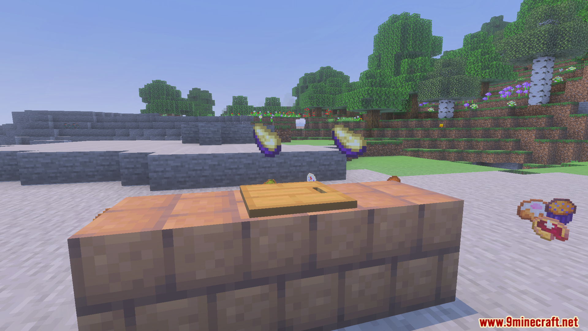Wooden cutting board on blocks with new food items and pies nearby
