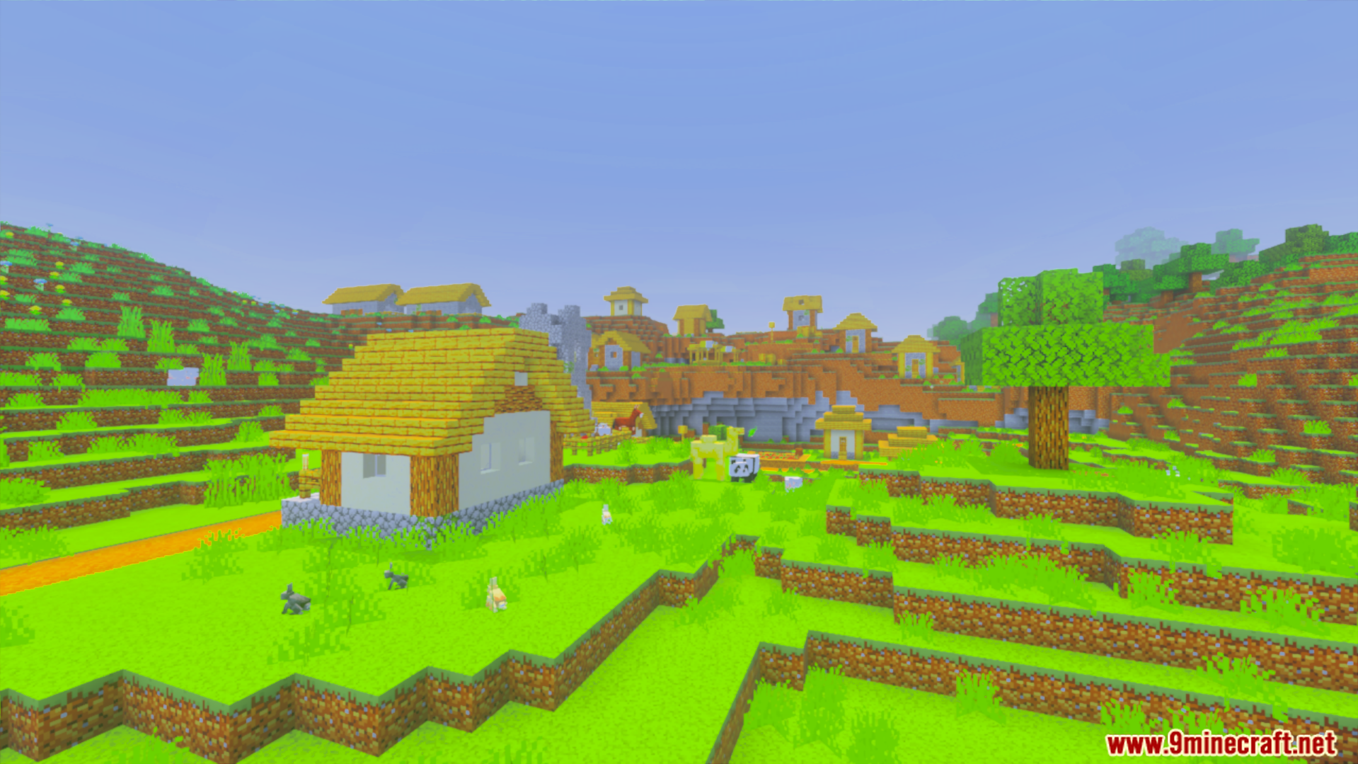 Village with bright green grass and houses under clear sky