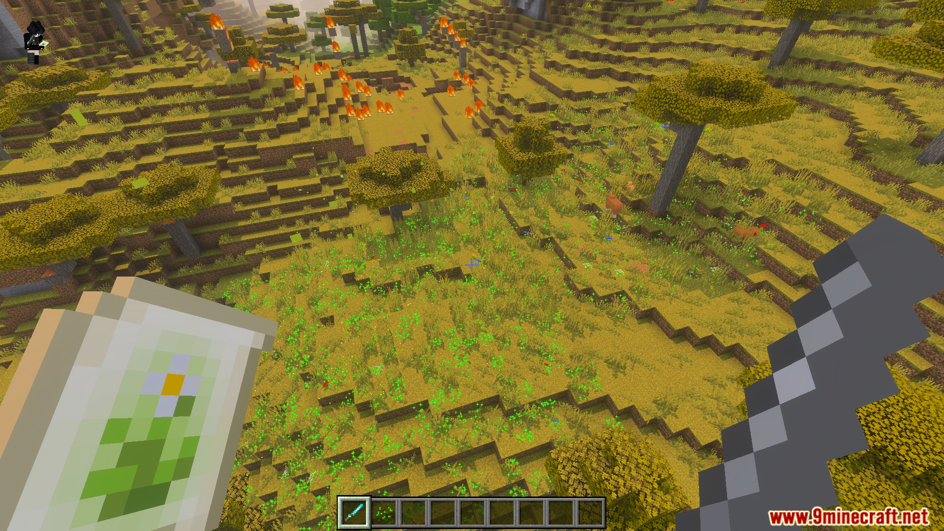 Player holding a magic spell scroll and sword in a savanna biome
