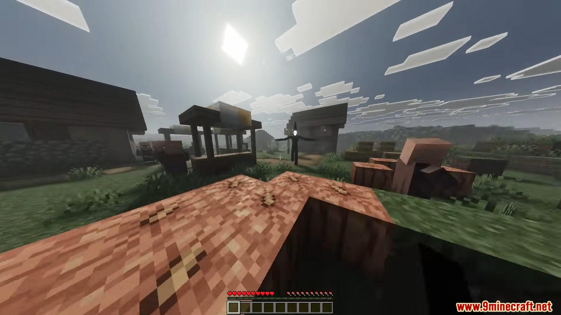 A tall dark entity with a white face standing in a village