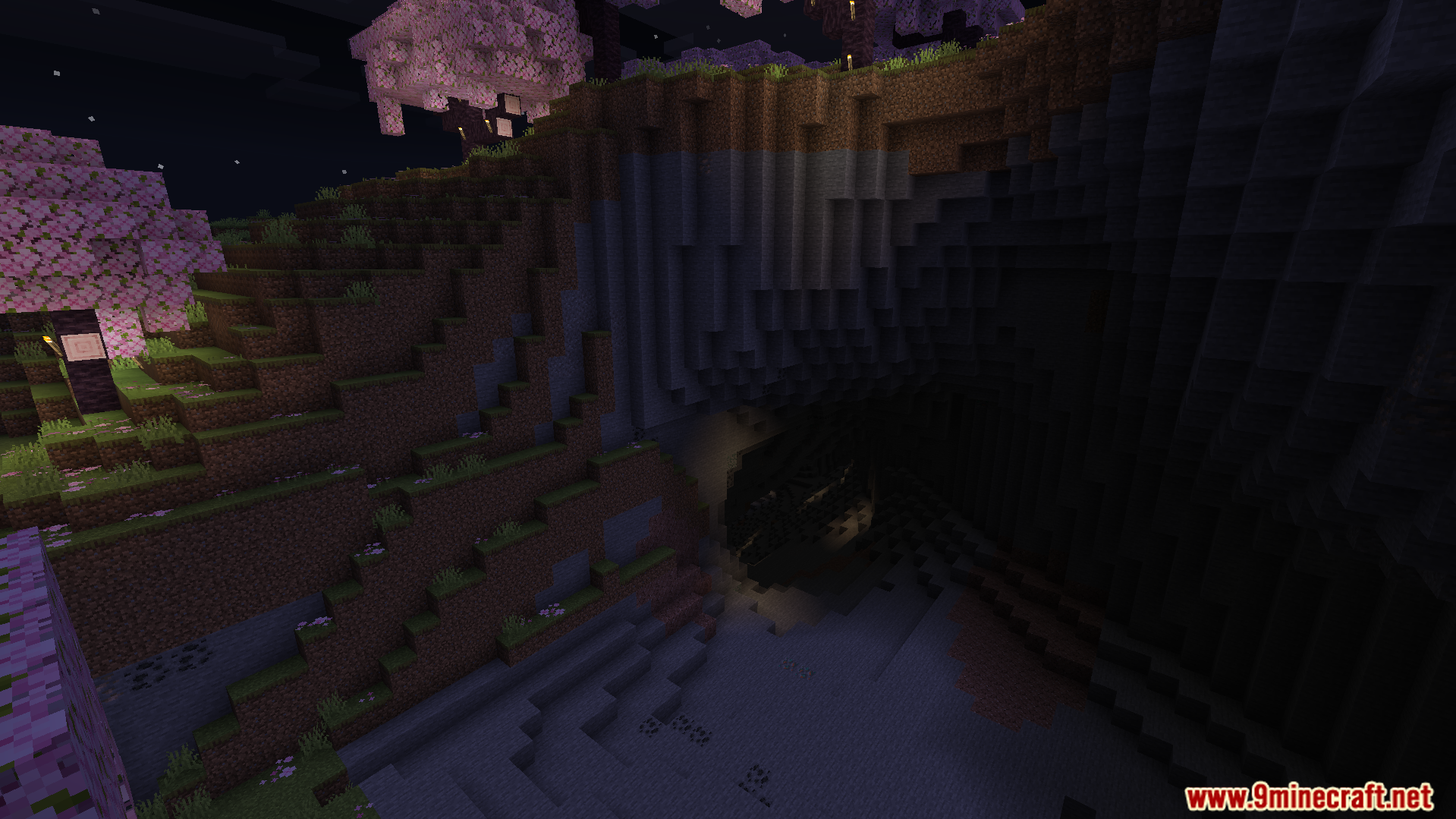 Rebuilt Shader Screenshot 5 A dark cave entrance nestled beneath a cherry blossom cliff at night