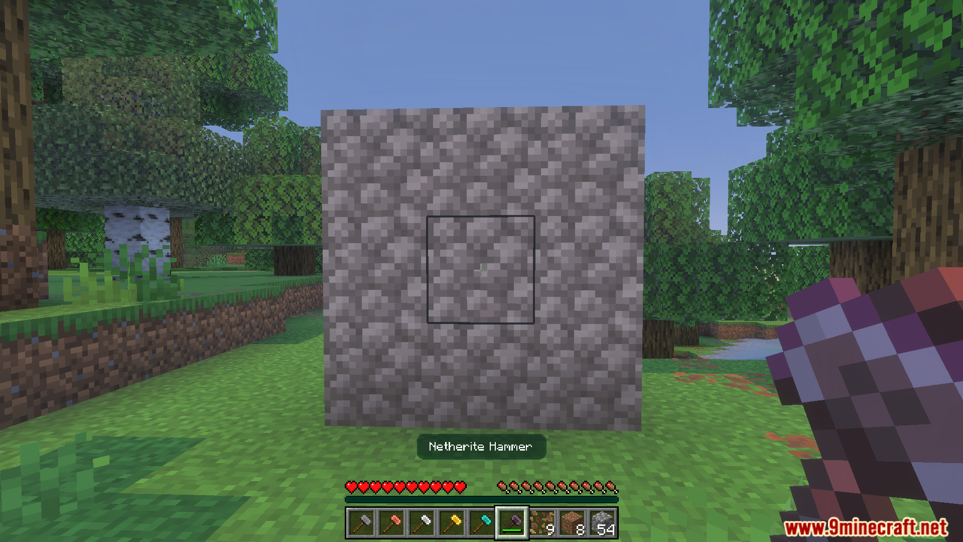 Player holding a netherite hammer facing a three by three wall of cobblestone