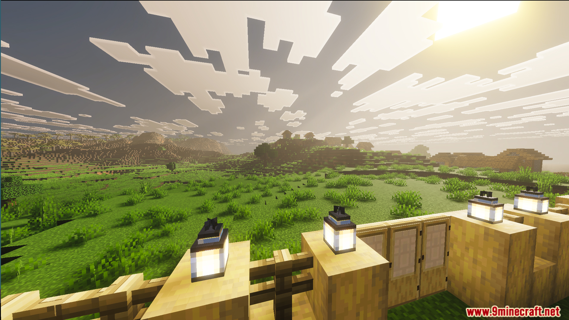 View of a lush plains biome and a village from the fenced garden