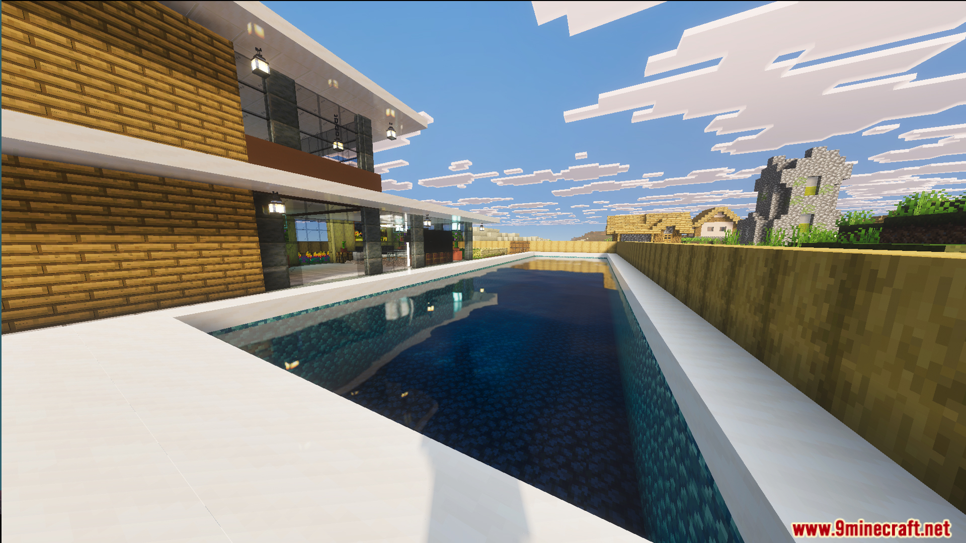 A long swimming pool sits next to the modern house near a village